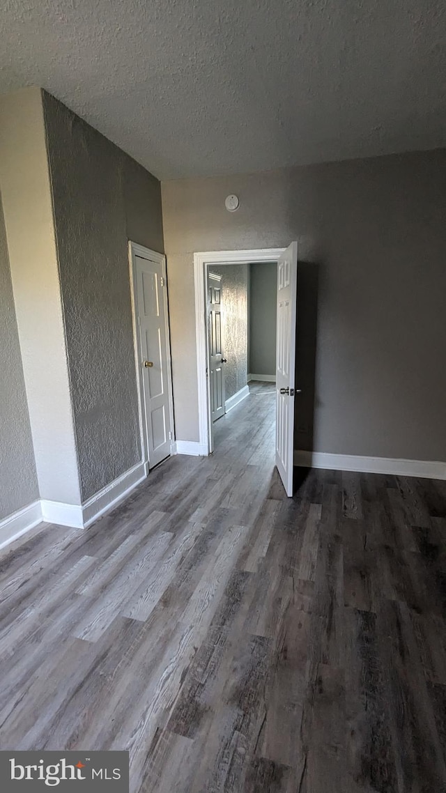 empty room with a textured ceiling and hardwood / wood-style flooring