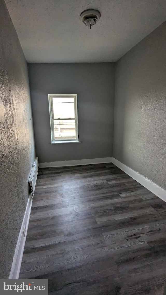 empty room with dark hardwood / wood-style floors and an AC wall unit