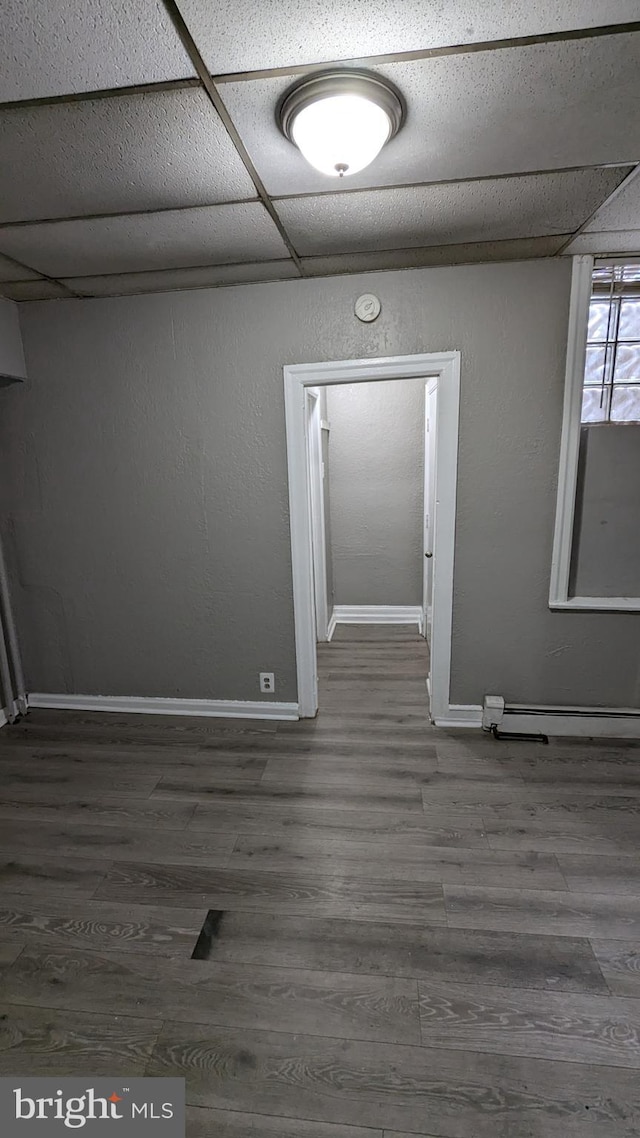 empty room featuring a paneled ceiling and dark hardwood / wood-style floors