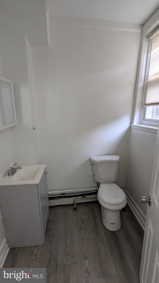 bathroom with hardwood / wood-style floors, vanity, toilet, and baseboard heating