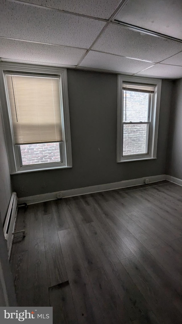 spare room featuring a paneled ceiling, a baseboard radiator, and dark hardwood / wood-style floors