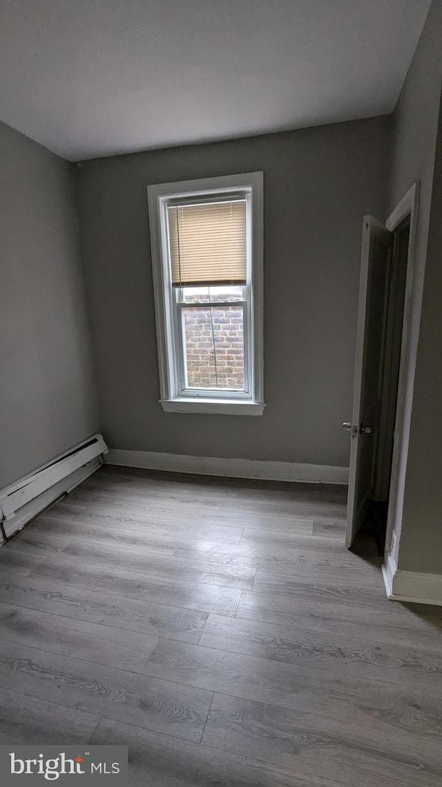 spare room featuring light wood-type flooring and a baseboard heating unit