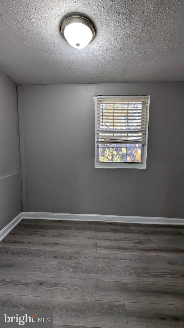 empty room with dark hardwood / wood-style floors and a textured ceiling