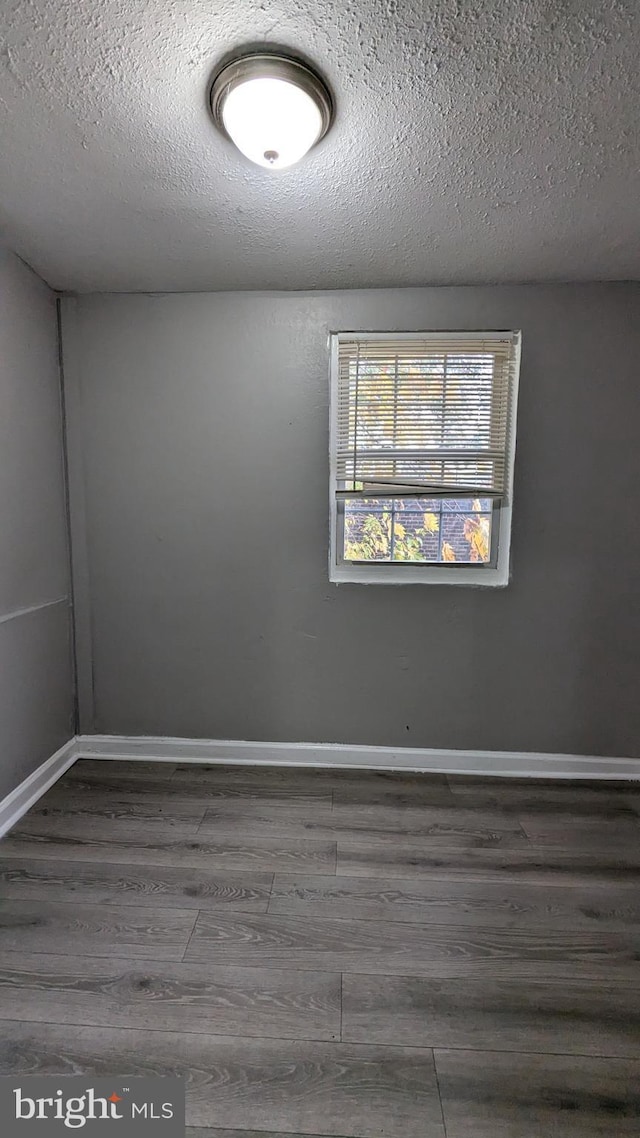 spare room featuring a textured ceiling and dark wood-type flooring