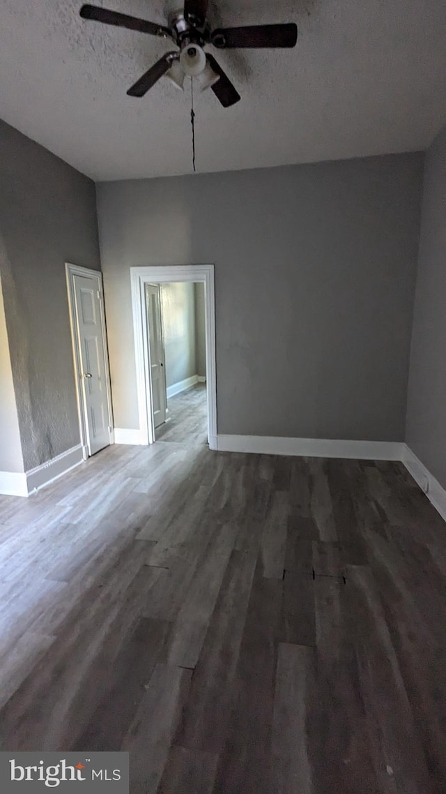 spare room with a textured ceiling, dark hardwood / wood-style flooring, and ceiling fan