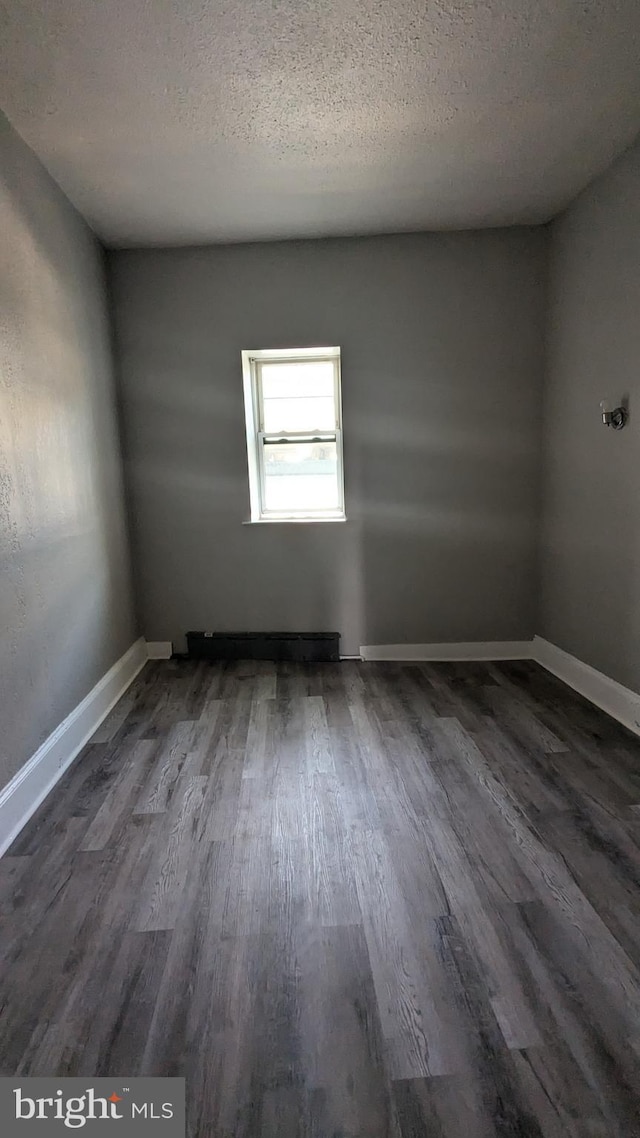 empty room featuring a textured ceiling and dark hardwood / wood-style flooring