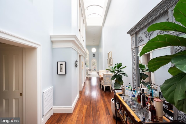 corridor featuring a towering ceiling and dark hardwood / wood-style flooring