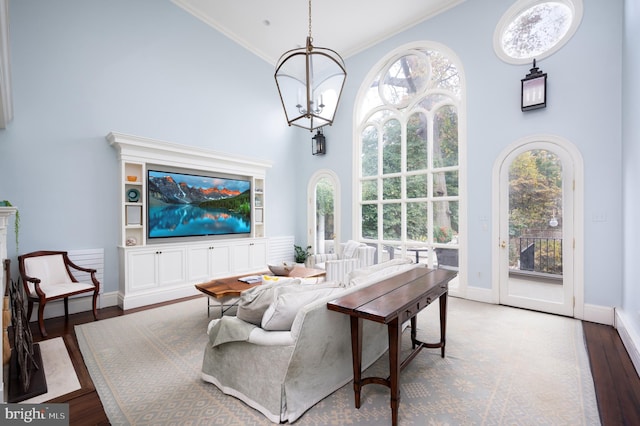 living room with hardwood / wood-style flooring, ornamental molding, a high ceiling, and an inviting chandelier