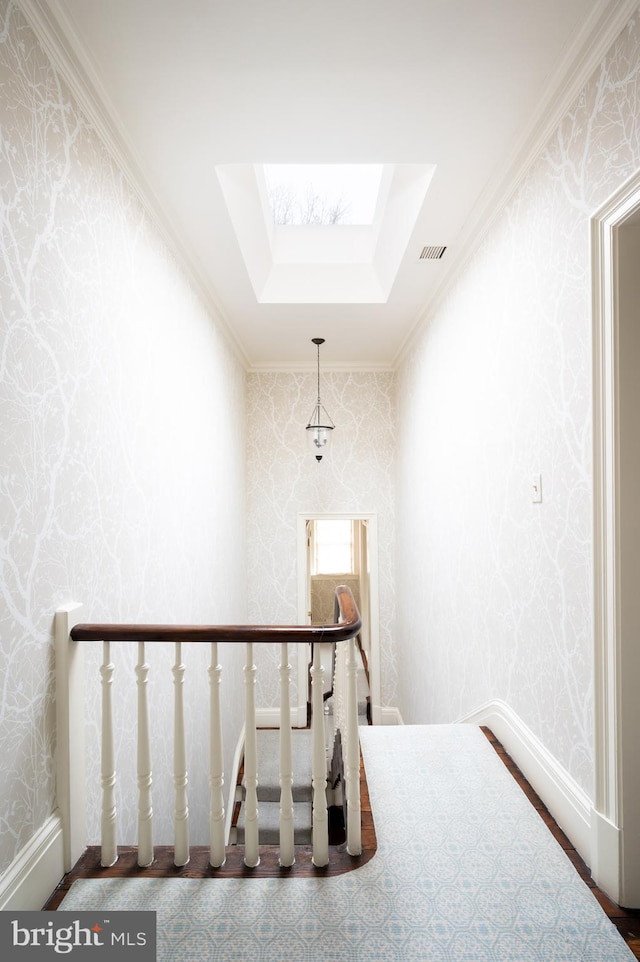 staircase with a skylight and crown molding