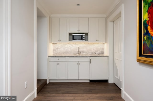 kitchen featuring white cabinets, decorative backsplash, light stone counters, and sink