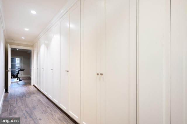 hallway with crown molding and light wood-type flooring