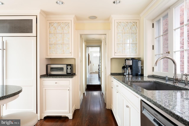 kitchen featuring dishwasher, sink, dark hardwood / wood-style flooring, dark stone counters, and white cabinets