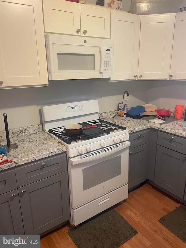 kitchen featuring gray cabinets, white cabinetry, white appliances, and dark wood-type flooring