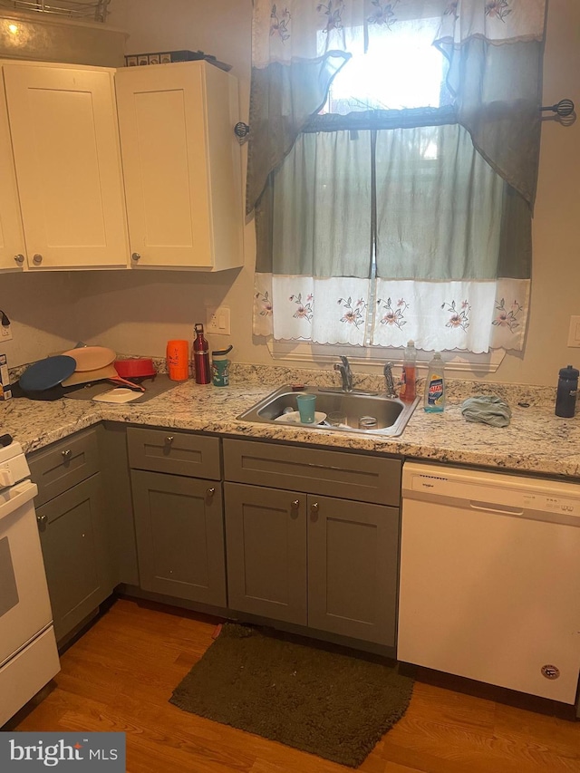 kitchen featuring white cabinetry, white appliances, sink, and light hardwood / wood-style flooring