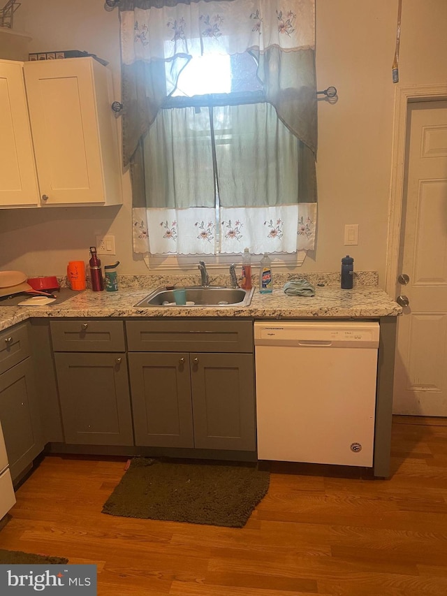 kitchen with dishwasher, white cabinets, light hardwood / wood-style flooring, and sink