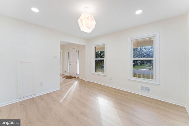 empty room with plenty of natural light and light hardwood / wood-style floors