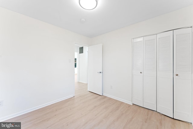 unfurnished bedroom with light wood-type flooring and a closet