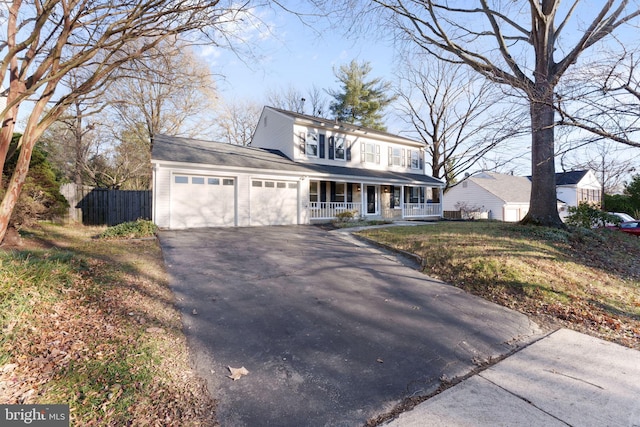 view of property featuring covered porch, a garage, and a front yard