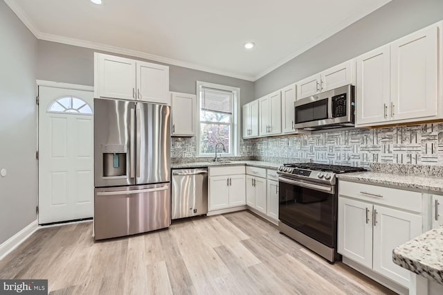 kitchen featuring white cabinets, backsplash, light hardwood / wood-style floors, and stainless steel appliances