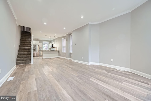 unfurnished living room featuring light wood-type flooring and ornamental molding