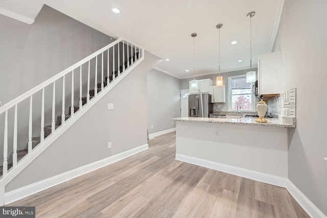 kitchen featuring tasteful backsplash, stainless steel refrigerator with ice dispenser, crown molding, light hardwood / wood-style floors, and white cabinets