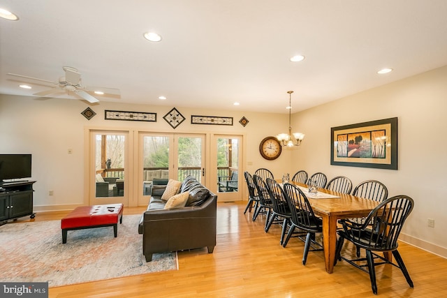 dining area with ceiling fan with notable chandelier and light hardwood / wood-style flooring