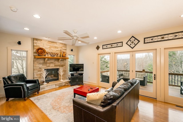 living room featuring ceiling fan, light wood-type flooring, and a fireplace