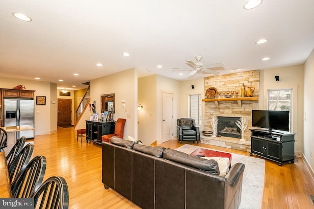 living room featuring a fireplace, light wood-type flooring, and ceiling fan