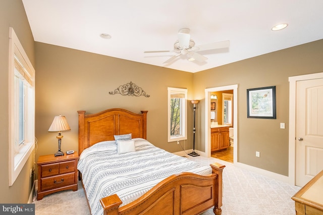 carpeted bedroom with ensuite bathroom and ceiling fan