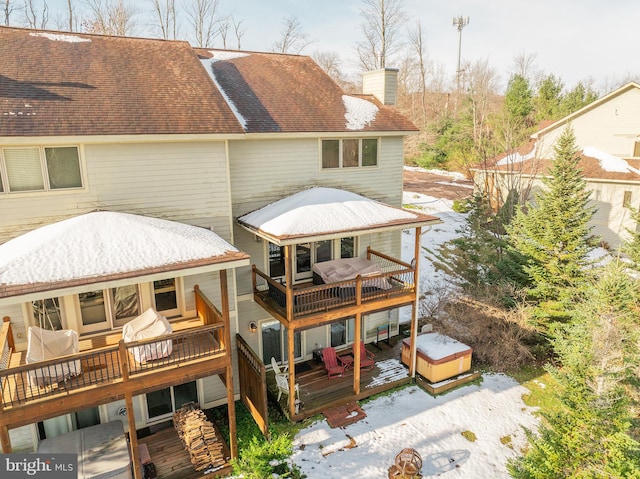 rear view of house featuring a wooden deck and a hot tub