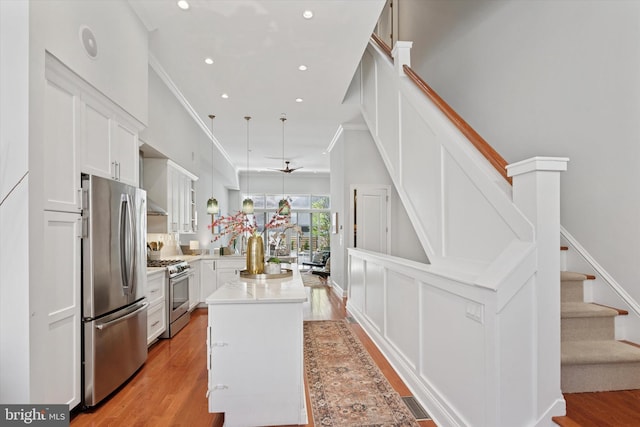 kitchen featuring light wood-style floors, a center island, light countertops, white cabinets, and appliances with stainless steel finishes