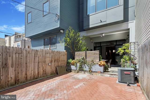 entrance to property with a patio, central AC, and fence