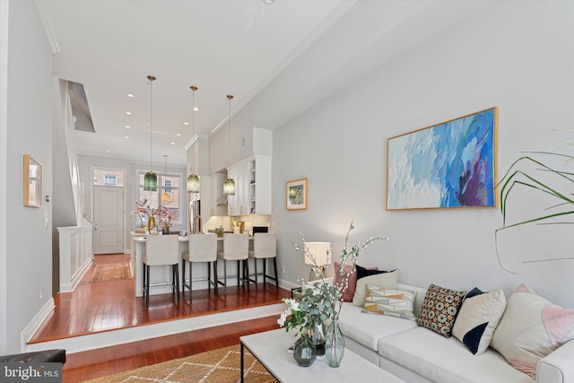 living area with baseboards, ornamental molding, recessed lighting, and wood finished floors