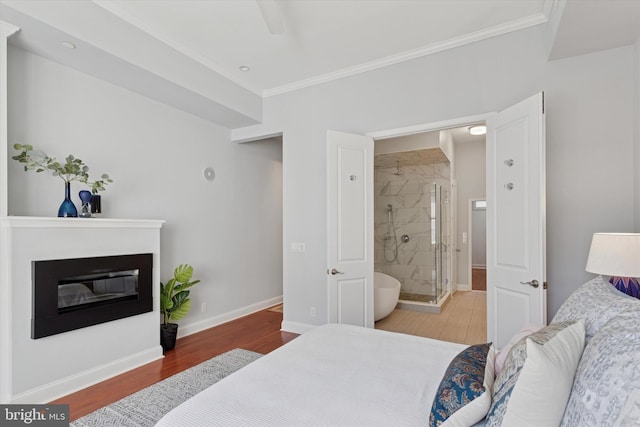 bedroom featuring crown molding, a glass covered fireplace, a ceiling fan, baseboards, and wood finished floors