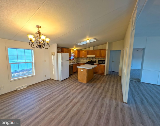 kitchen featuring a center island, hanging light fixtures, hardwood / wood-style floors, white fridge, and stainless steel stove