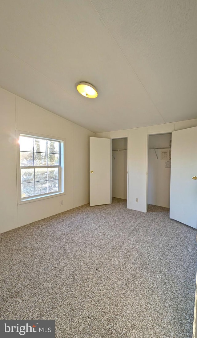 unfurnished bedroom with carpet floors and multiple closets