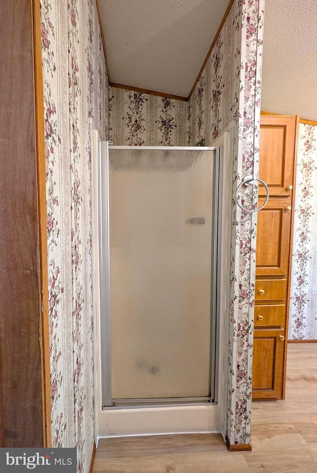 bathroom featuring a textured ceiling, lofted ceiling, wood-type flooring, and a shower with door