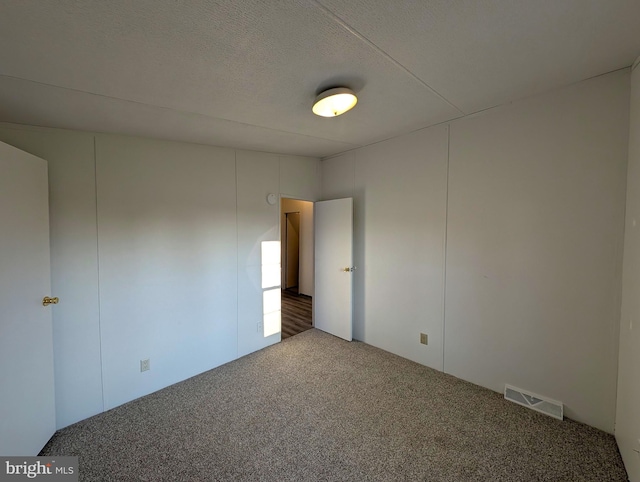 carpeted spare room with a textured ceiling