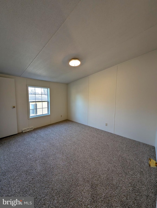 carpeted spare room with a textured ceiling