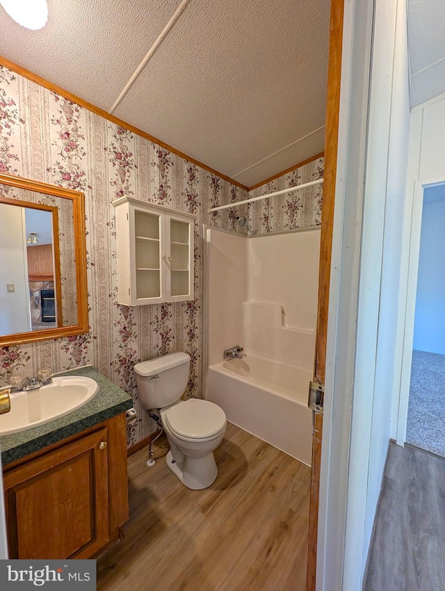 full bathroom featuring hardwood / wood-style flooring, toilet, a textured ceiling, and bathing tub / shower combination