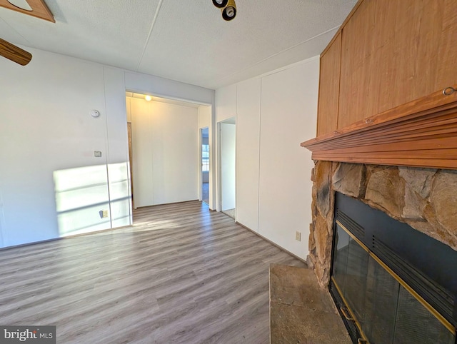 unfurnished living room featuring a fireplace, a textured ceiling, and light wood-type flooring