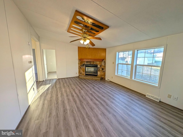 unfurnished living room featuring a fireplace, a textured ceiling, light wood-type flooring, and ceiling fan