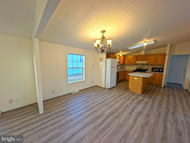 kitchen featuring tasteful backsplash, decorative light fixtures, light hardwood / wood-style flooring, white fridge, and a kitchen island