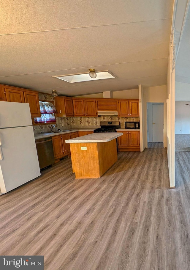 kitchen featuring tasteful backsplash, ventilation hood, stainless steel appliances, light hardwood / wood-style flooring, and a kitchen island