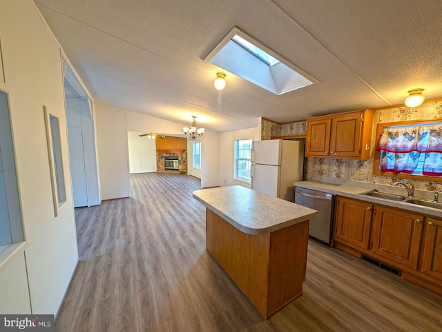 kitchen featuring stainless steel dishwasher, white refrigerator, lofted ceiling with skylight, light hardwood / wood-style floors, and a kitchen island