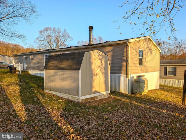 rear view of property featuring a lawn and a storage unit