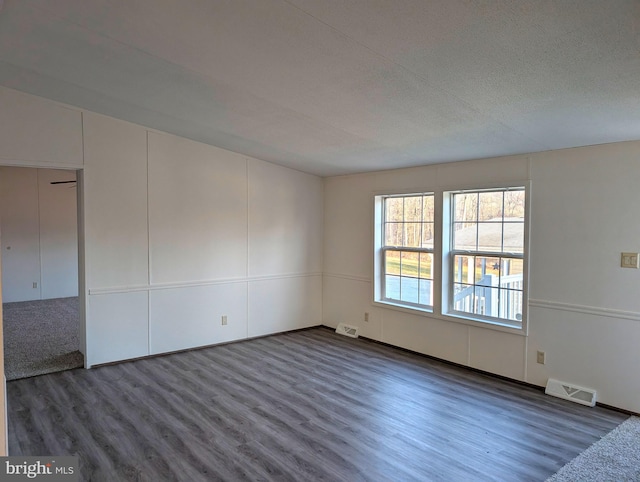 empty room with a textured ceiling and dark hardwood / wood-style floors