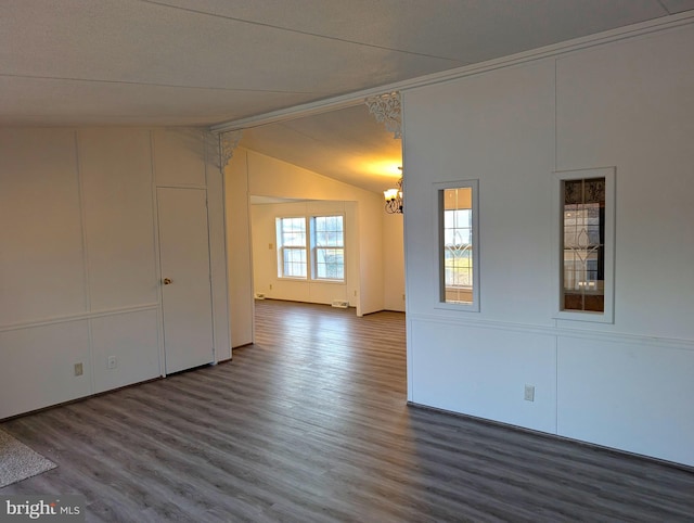 spare room with a textured ceiling, wood-type flooring, lofted ceiling, and an inviting chandelier