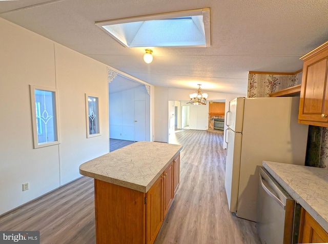 kitchen with a center island, lofted ceiling with skylight, hanging light fixtures, light wood-type flooring, and appliances with stainless steel finishes