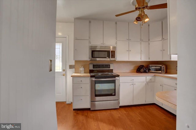 kitchen with white cabinets, backsplash, stainless steel appliances, and light hardwood / wood-style flooring